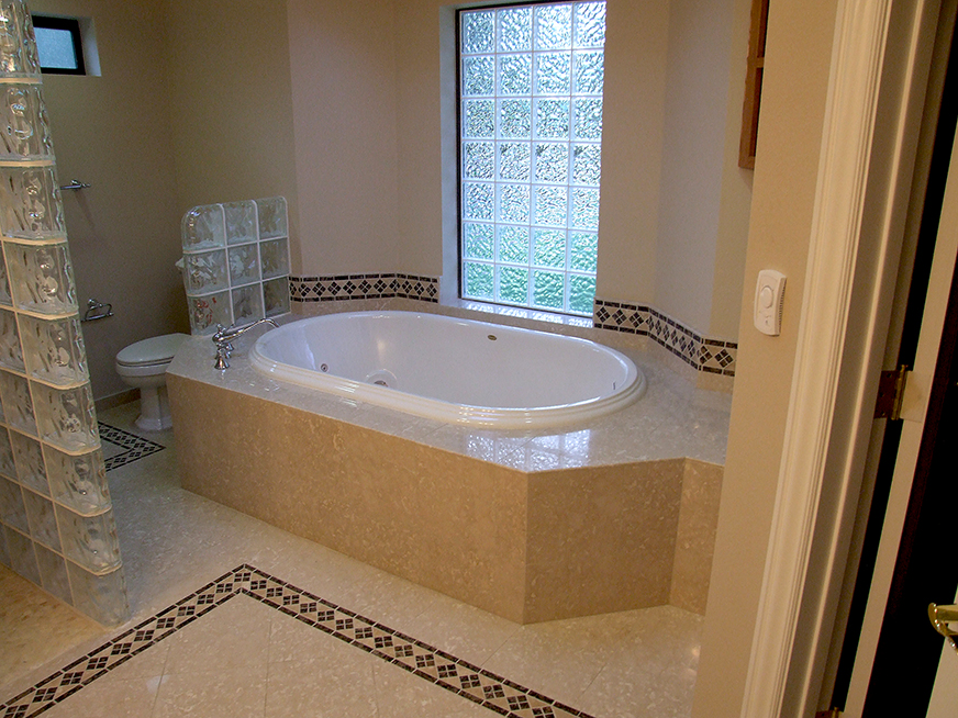 Stone tiling in bathroom, floor, jacuzzi, glass block window, glass wall, floor and wall stone inlays and detailing.