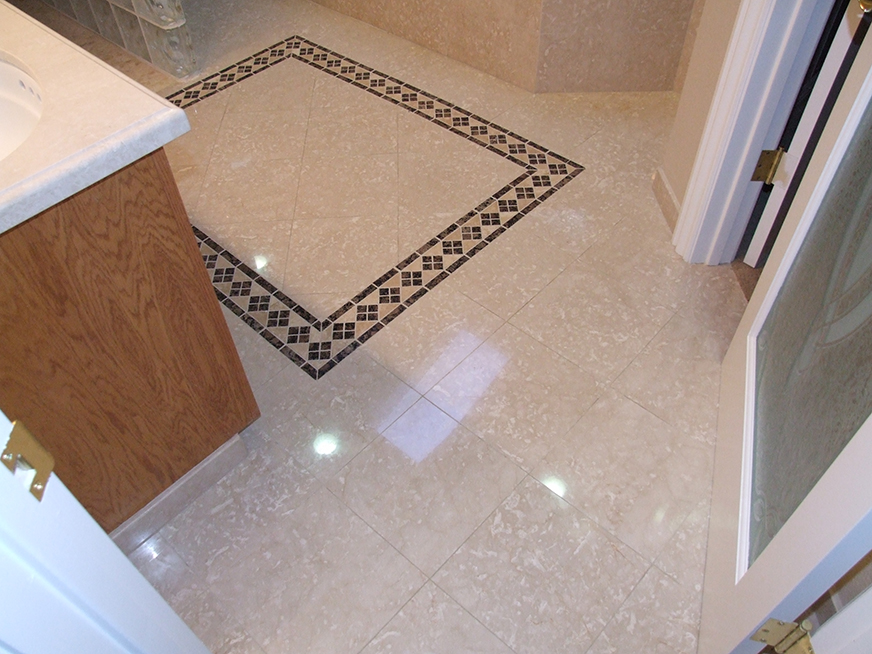 Beautiful polished stone tile flooring with insets in bathroom. Engineered stone countertops.