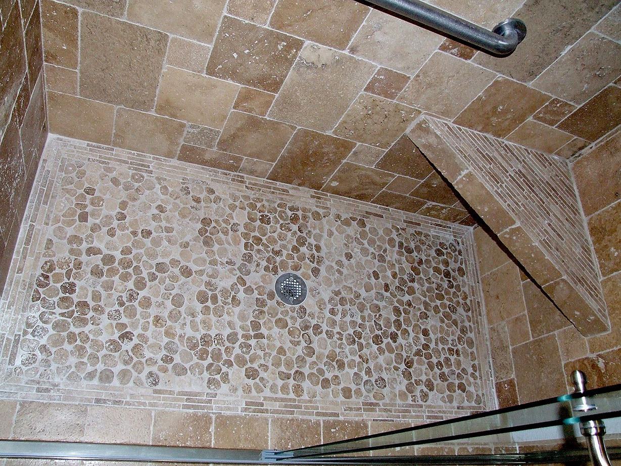 Stone tile walls and sliced river rock flooring for shower stall.